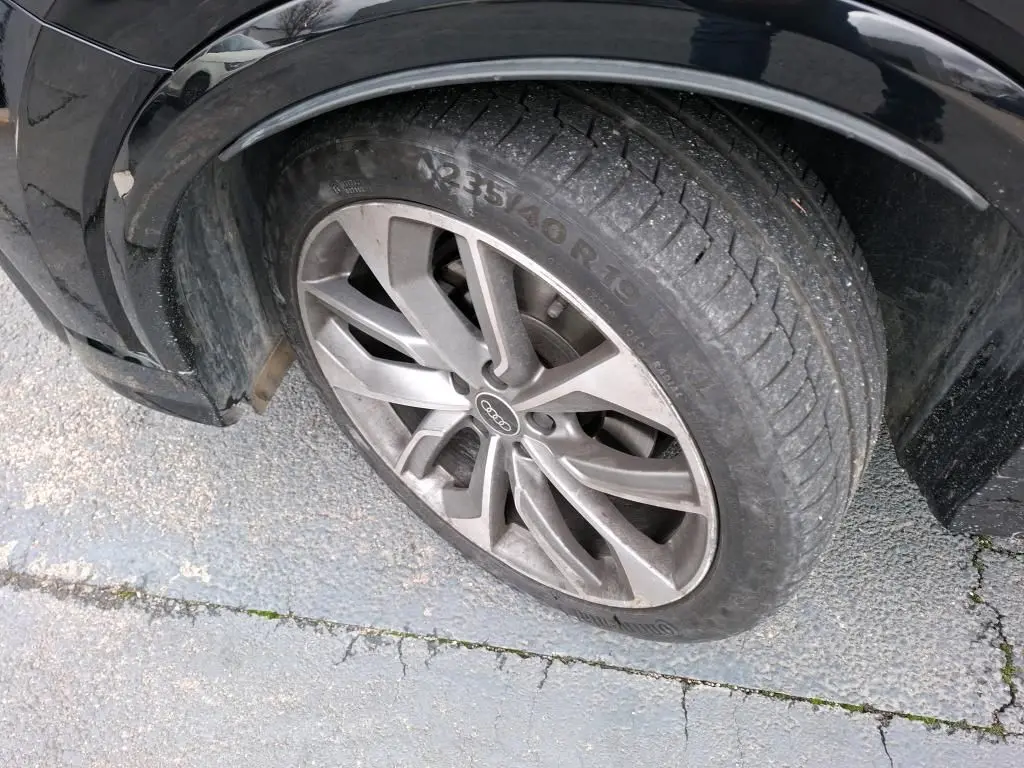 Gros plan sur la roue avant gauche noire d’un Audi Q2 2023 avec jante alu à 5 doubles branches.