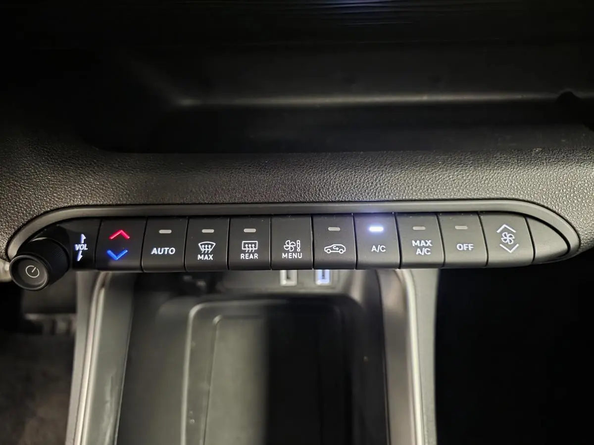 Vue rapprochée des commandes de climatisation et volume du Jeep Avenger 2025, boutons noirs avec éclairage blanc et rouge.