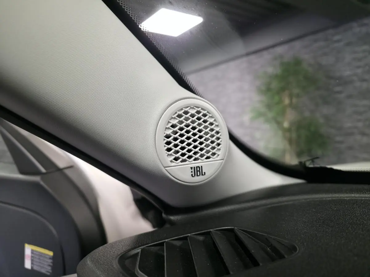 Gros plan sur l'enceinte JBL blanche intégrée à l'angle avant gauche du tableau de bord du Jeep Avenger blanc.