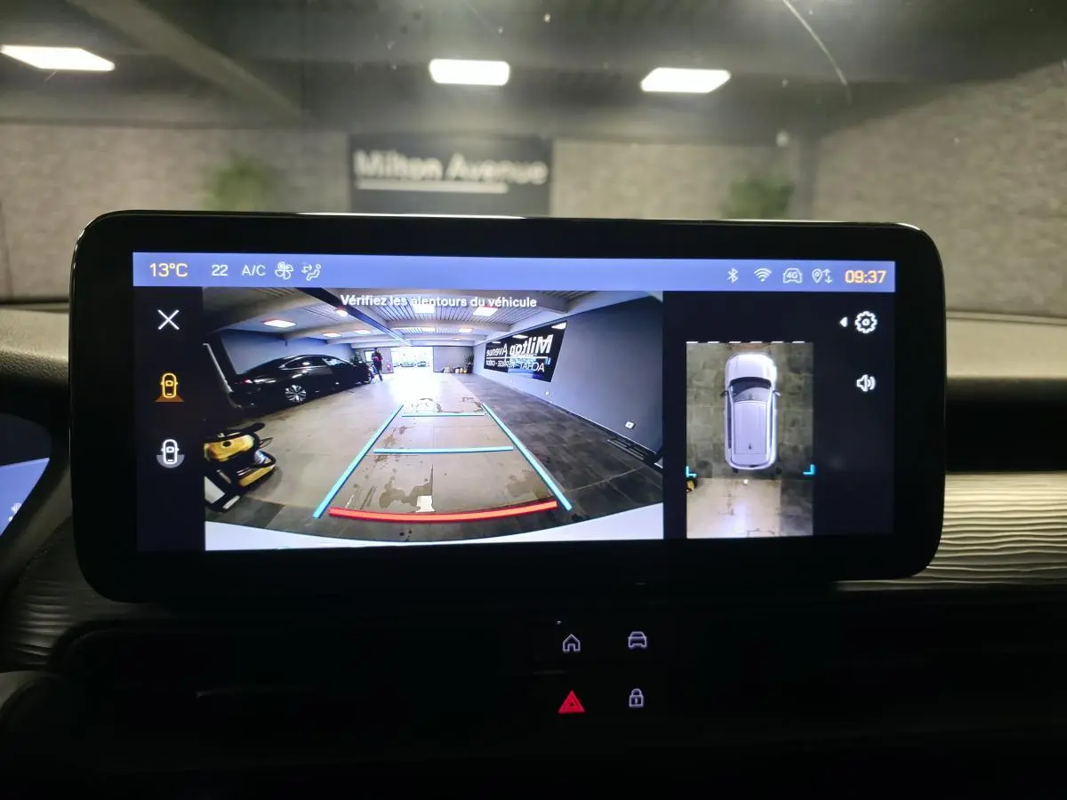 Écran tactile intérieur montrant la caméra de recul et vue 360° du Jeep Avenger blanc, tableau de bord en arrière-plan.