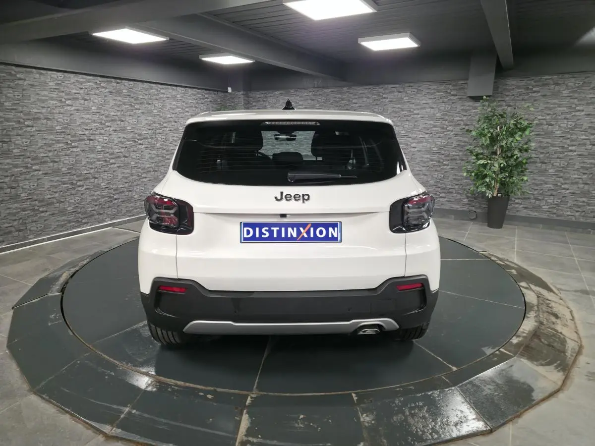 Vue arrière d'un Jeep Avenger blanc 2025 avec feux arrière noirs et hayon électrique mains libres.