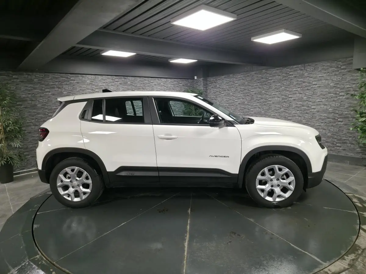 Vue de profil côté gauche d'un Jeep Avenger blanc avec jantes alliage 17 pouces dans un showroom intérieur.