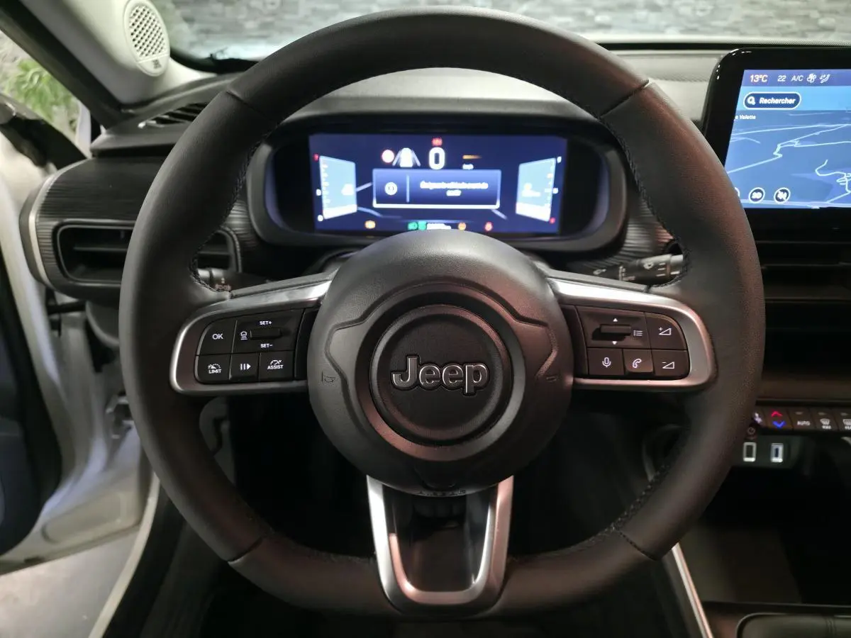 Vue intérieure centrée sur le volant noir du Jeep Avenger 2025 avec tableau de bord numérique et écran tactile.