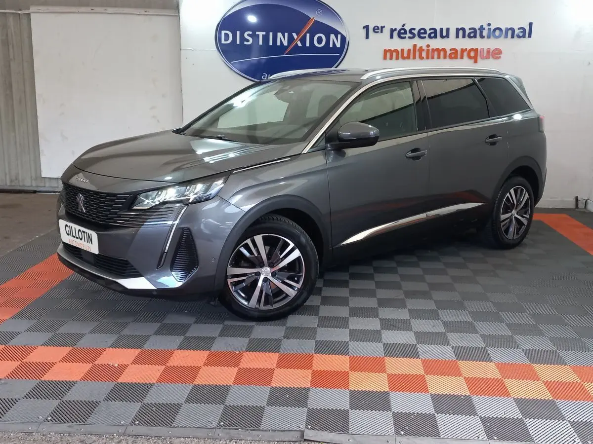 Peugeot 5008 gris foncé vue 3/4 avant droit, avec jantes alliage et toit noir en showroom.