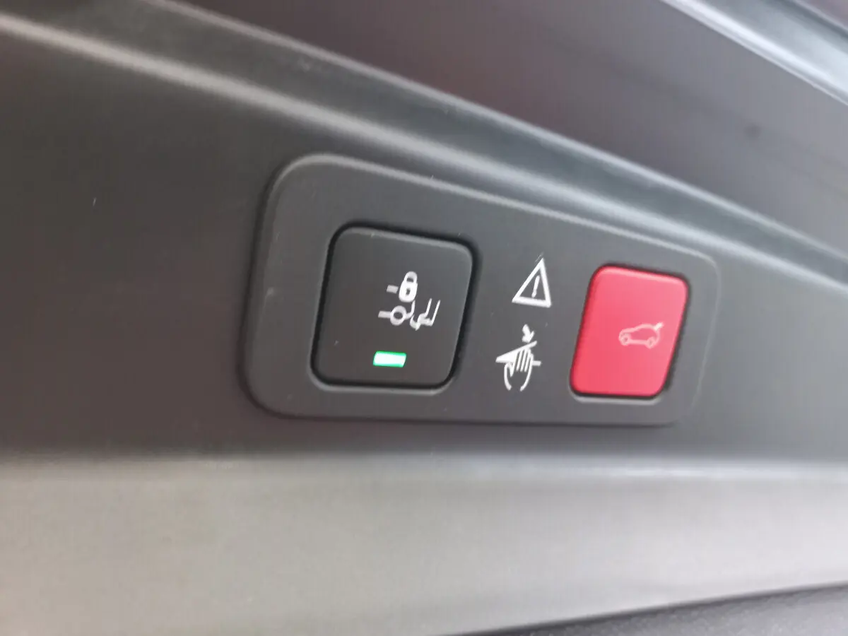 Gros plan sur les boutons de commande du hayon et des sièges arrière dans un Peugeot 5008 gris foncé de 2021.