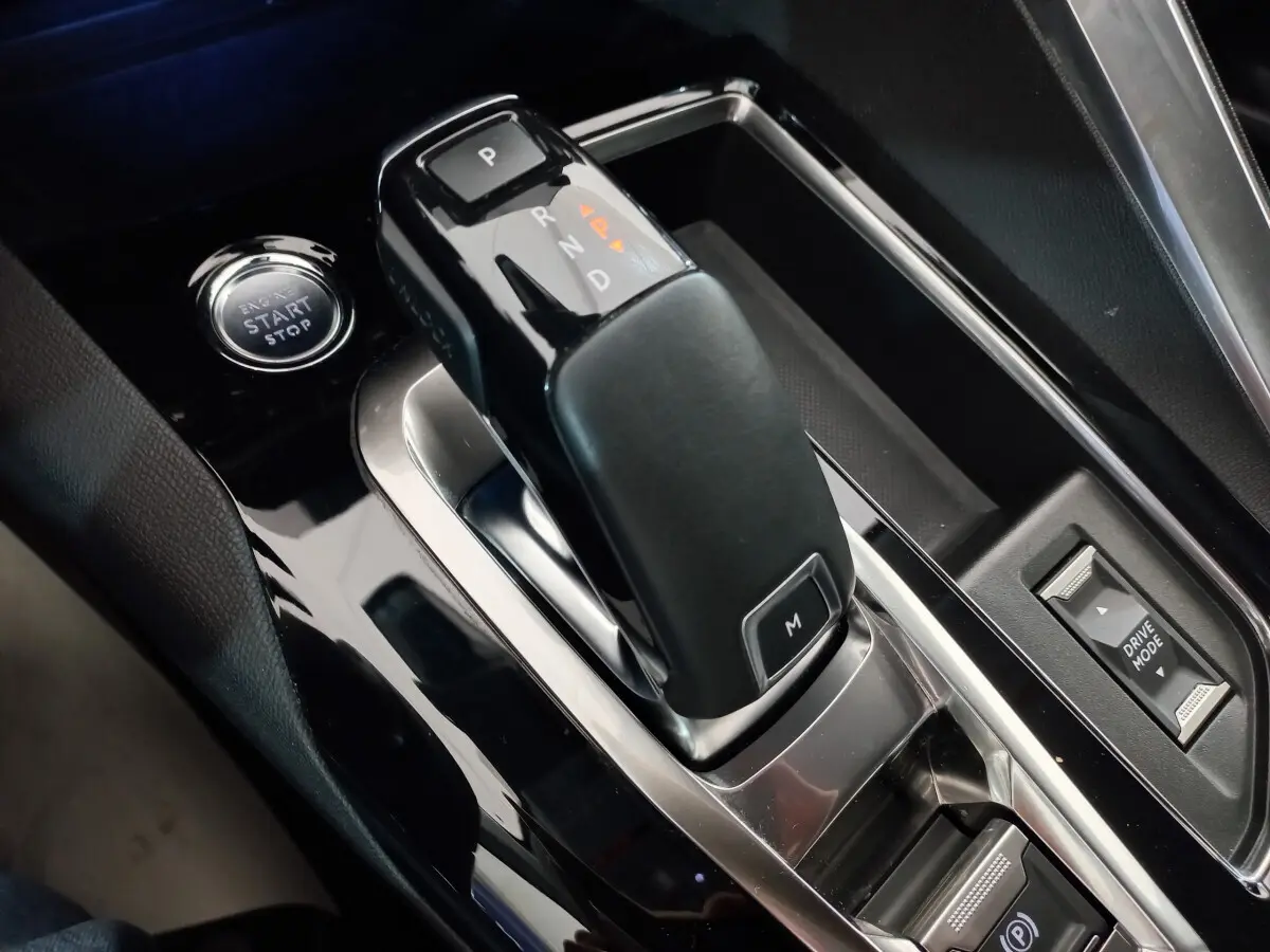 Gros plan sur la console centrale noire brillante du Peugeot 5008 2021, avec levier de vitesse automatique et bouton start/stop.