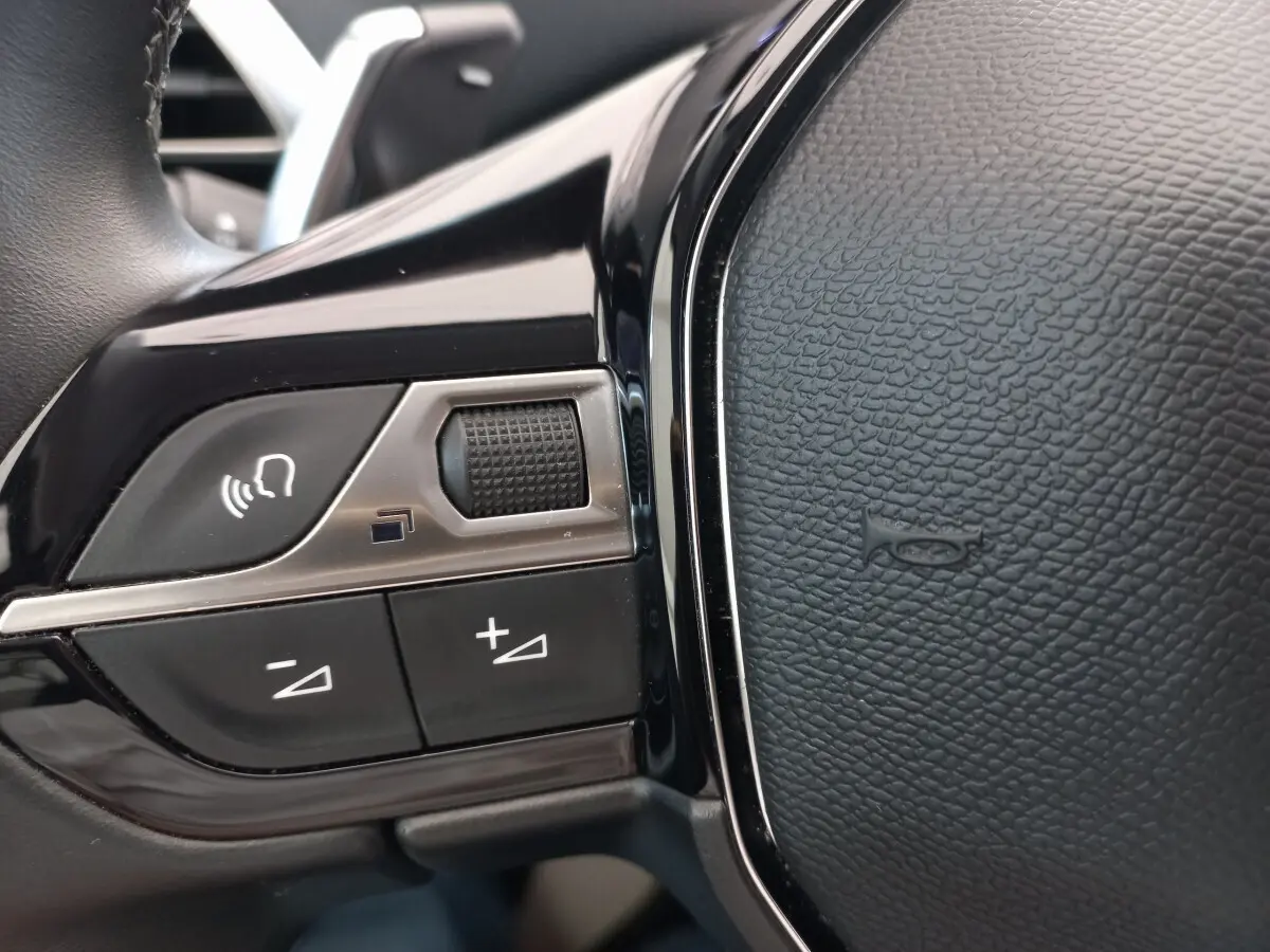 Gros plan sur les commandes vocales et volume du volant cuir noir du Peugeot 5008 gris foncé 2021.