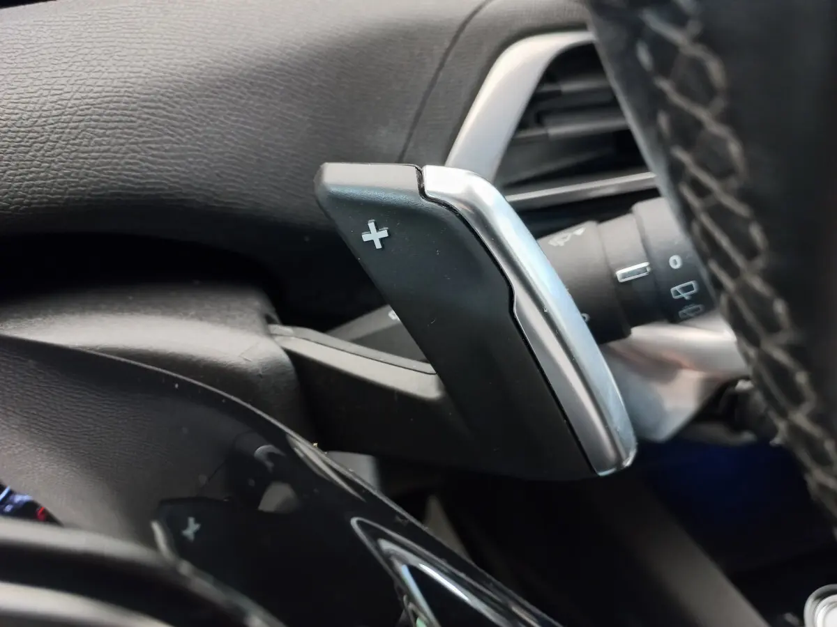 Gros plan sur la palette de changement de vitesse + côté droit du volant cuir noir du Peugeot 5008 gris foncé.