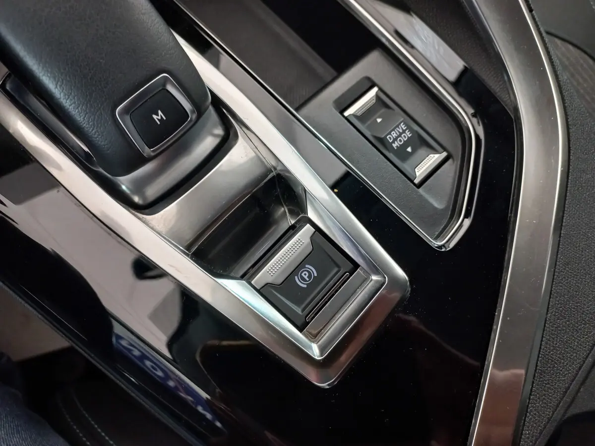 Gros plan sur la console centrale noire du Peugeot 5008 2021 avec bouton frein électrique et sélection mode de conduite.