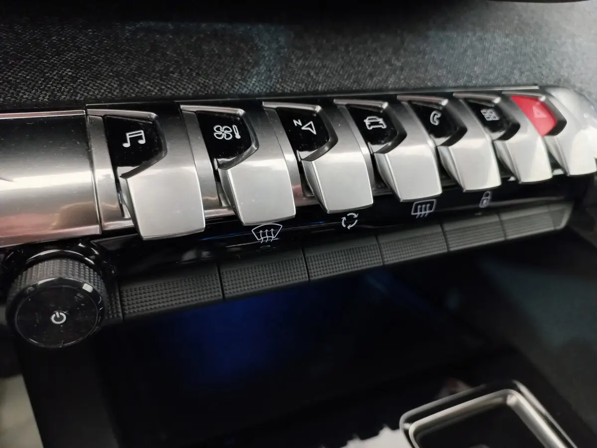 Gros plan sur les commandes chromées du tableau de bord du Peugeot 5008 gris foncé, version Allure Pack 2021.