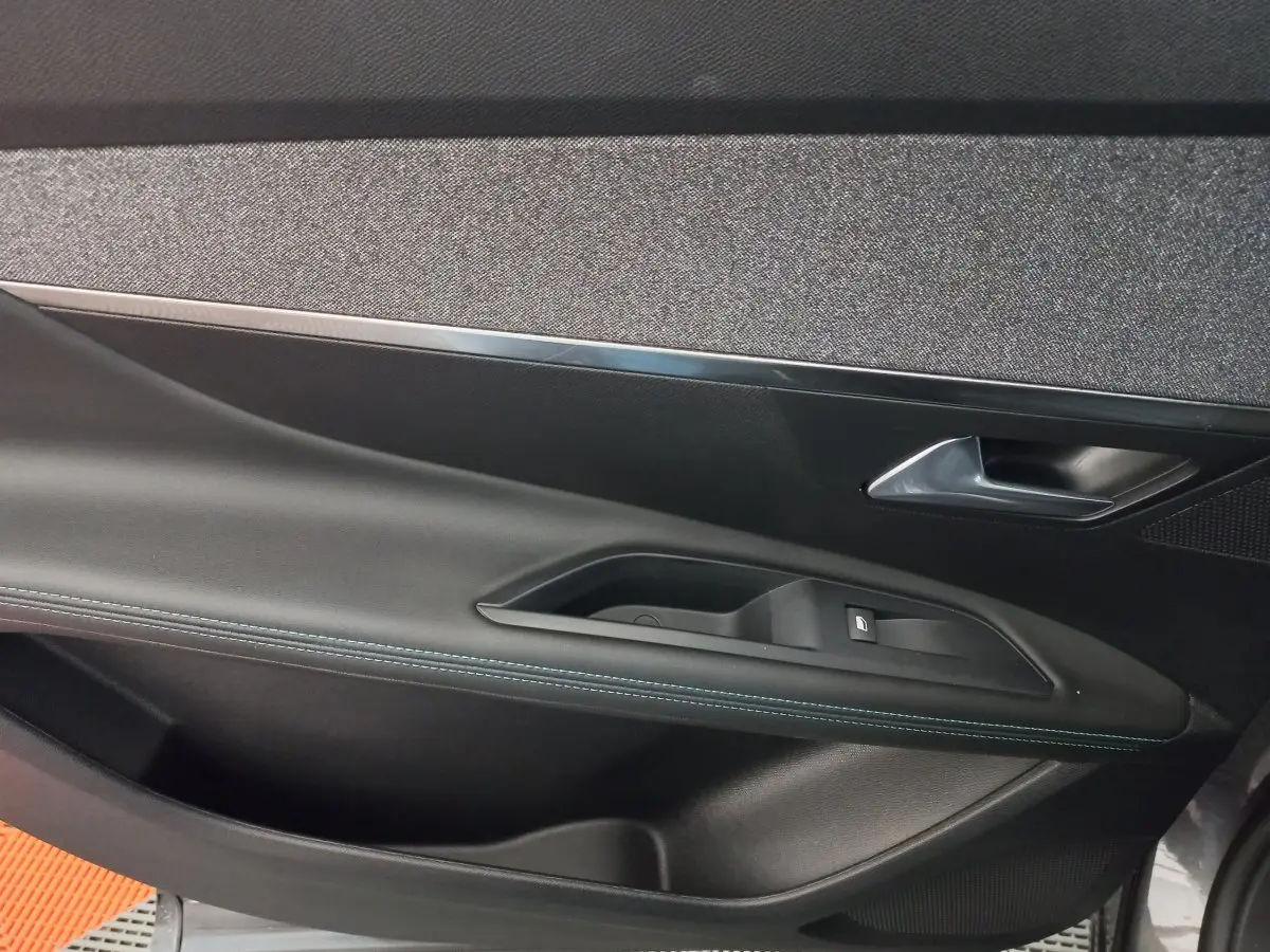 Gros plan sur la garniture de la porte côté gauche du Peugeot 5008 gris foncé, avec couture bleue visible.