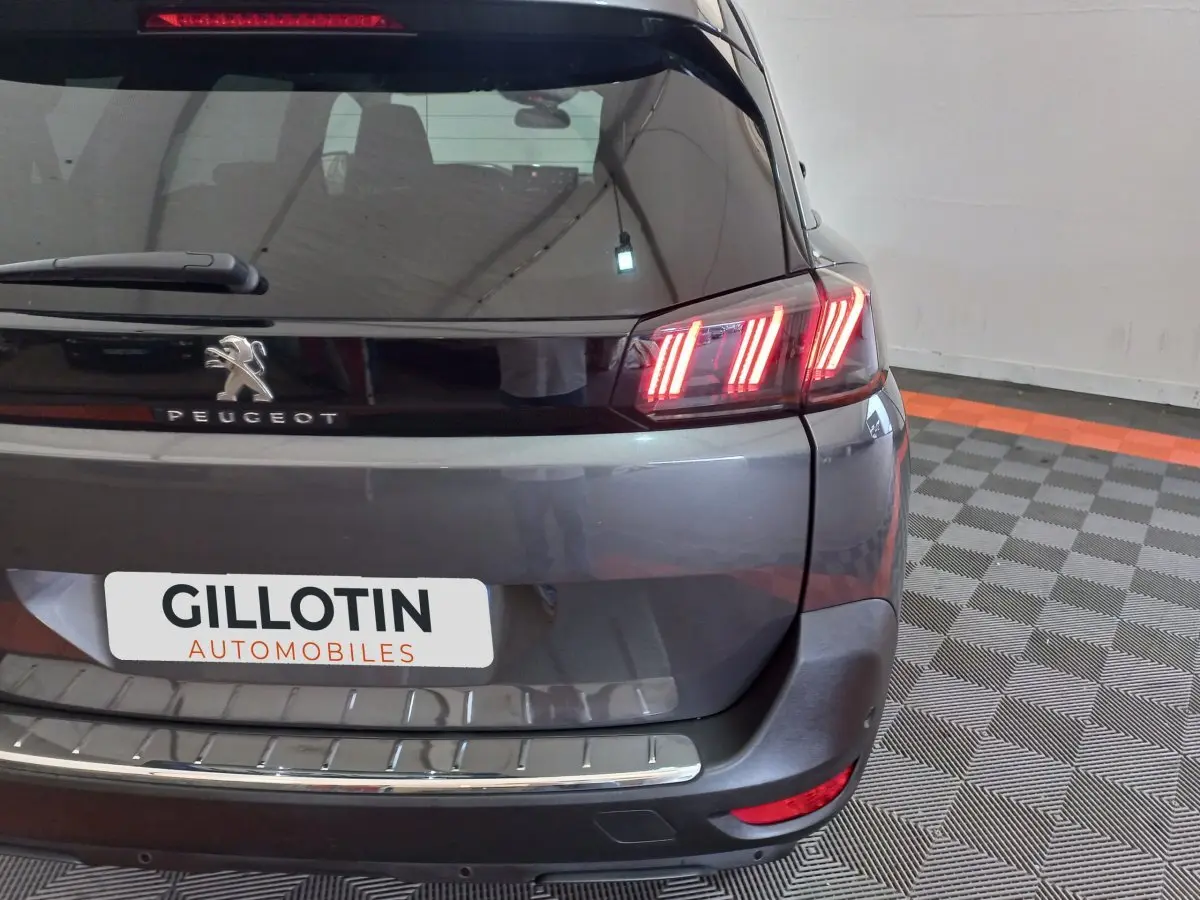 Vue arrière droite du Peugeot 5008 gris foncé avec feux LED distinctifs et logo Peugeot visible.