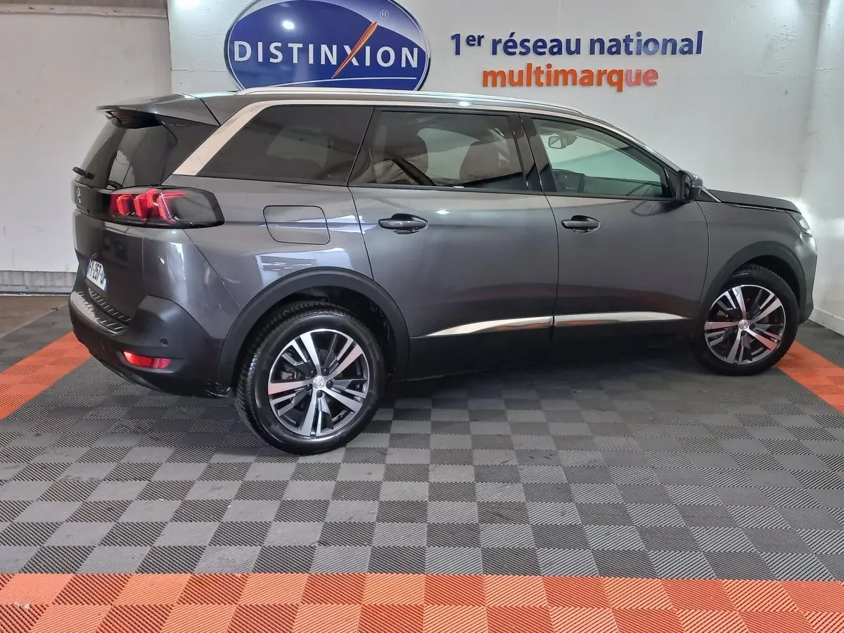 Peugeot 5008 gris foncé vue de profil côté droit, avec jantes alliage et toit noir en arrière-plan intérieur showroom.