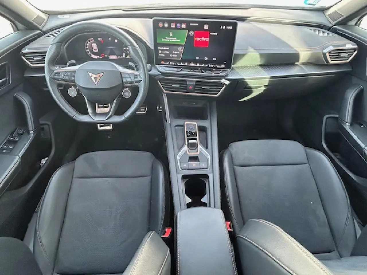 Vue intérieure avant du CUPRA Formentor 2025, tableau de bord moderne avec écran tactile et volant cuir noir.