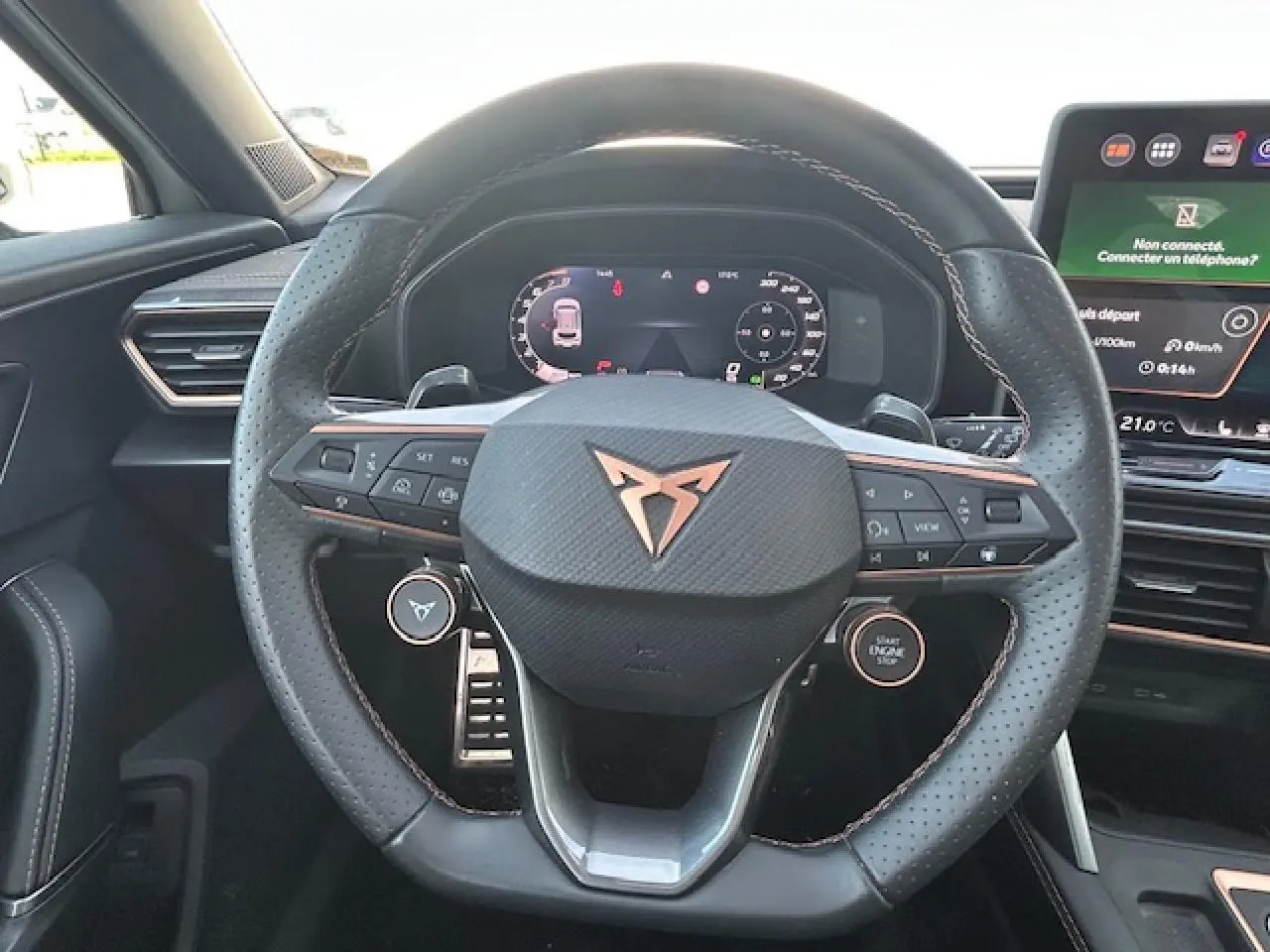 Vue rapprochée du volant cuir perforé avec logo CUPRA cuivré et tableau de bord digital du Formentor blanc neige 2025.