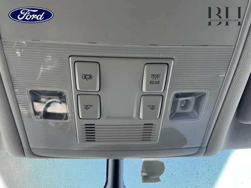 Panneau de commandes d'éclairage intérieur gris clair vu de dessous, avec boutons de plafonnier et détecteur de mouvement.