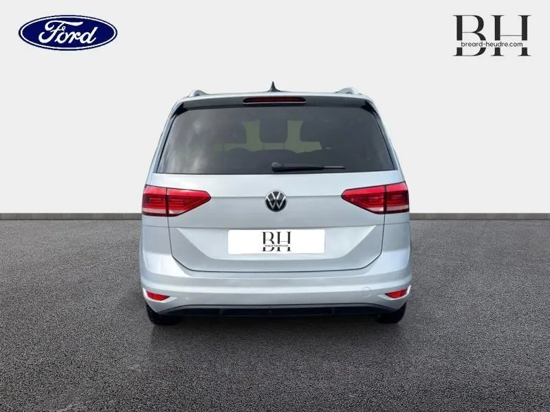Vue arrière d'un Volkswagen Touran 2021 Reflet d'Argent Métallisée avec vitres teintées et feux rouges distinctifs.