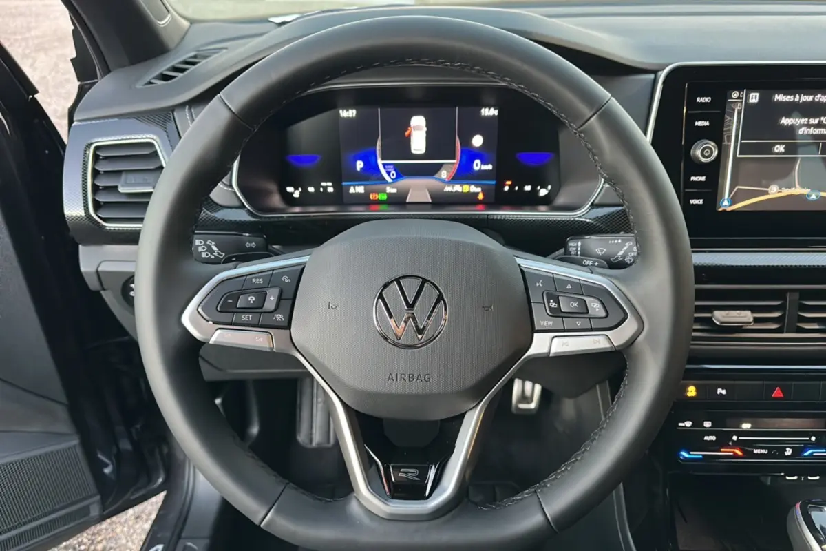 Vue rapprochée du volant cuir multifonctions et du tableau de bord digital du Volkswagen T-Cross gris cendré 2025.