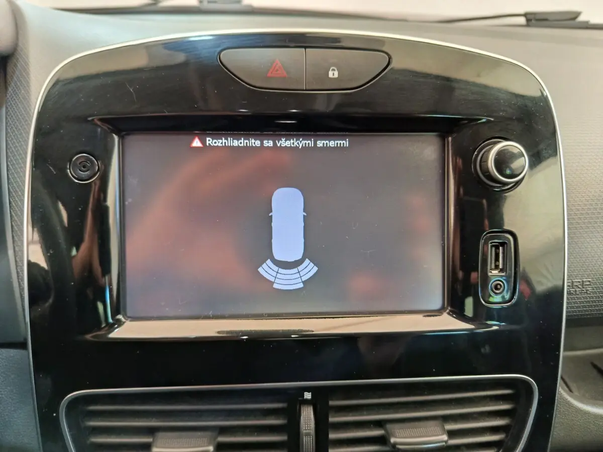 Écran tactile central affichant l'aide au stationnement arrière sur tableau de bord noir d'une Renault Clio Intens rouge.