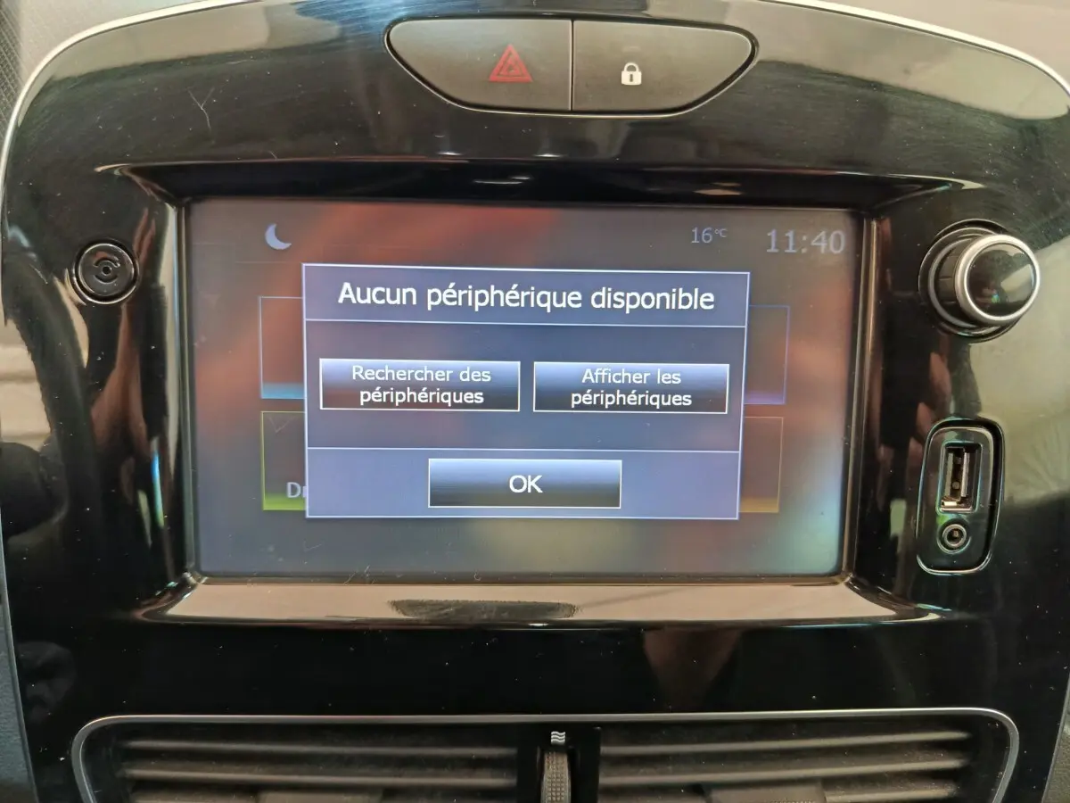 Écran tactile central de la Renault Clio Intens rouge de 2018 affichant un message Bluetooth, entouré de commandes noires brillantes.