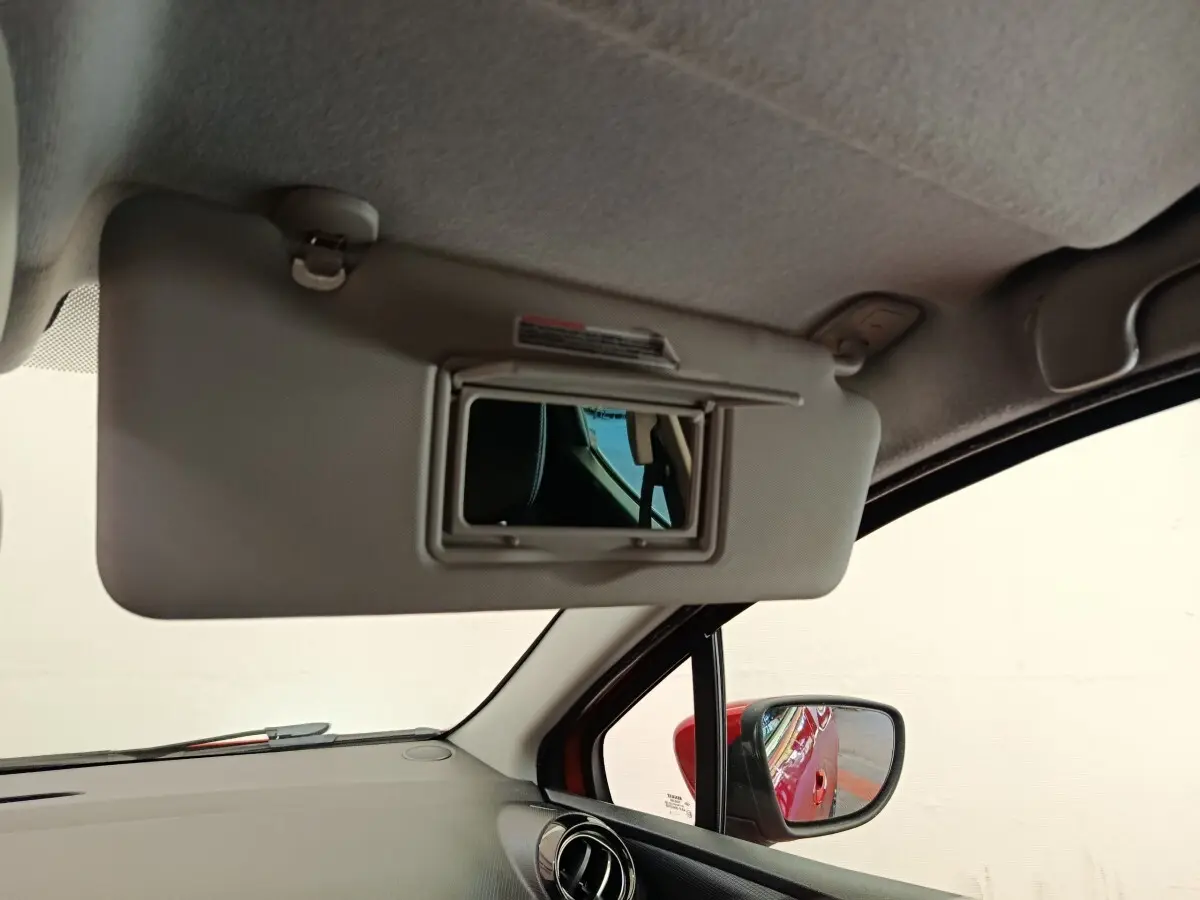Intérieur de la Renault Clio Intens rouge, vue côté passager avec pare-soleil et rétroviseur extérieur visible.