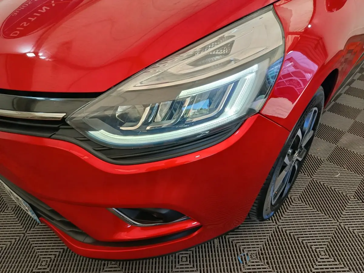 Gros plan sur l'avant droit rouge de la Renault Clio Intens 2018, mettant en valeur le phare LED et la jante noire.
