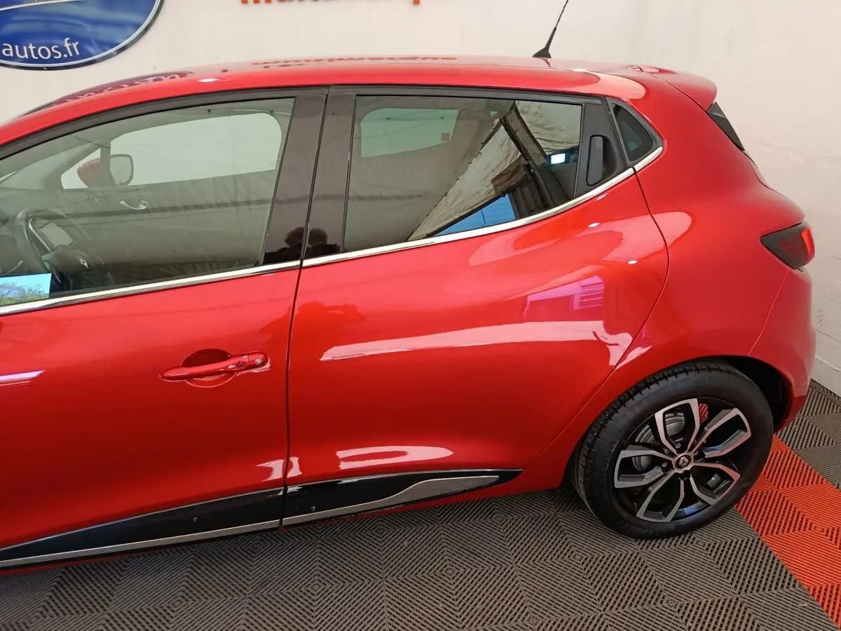 Vue latérale droite d'une Renault Clio Intens rouge de 2018, mettant en valeur la ligne fluide et les jantes alliage noires.