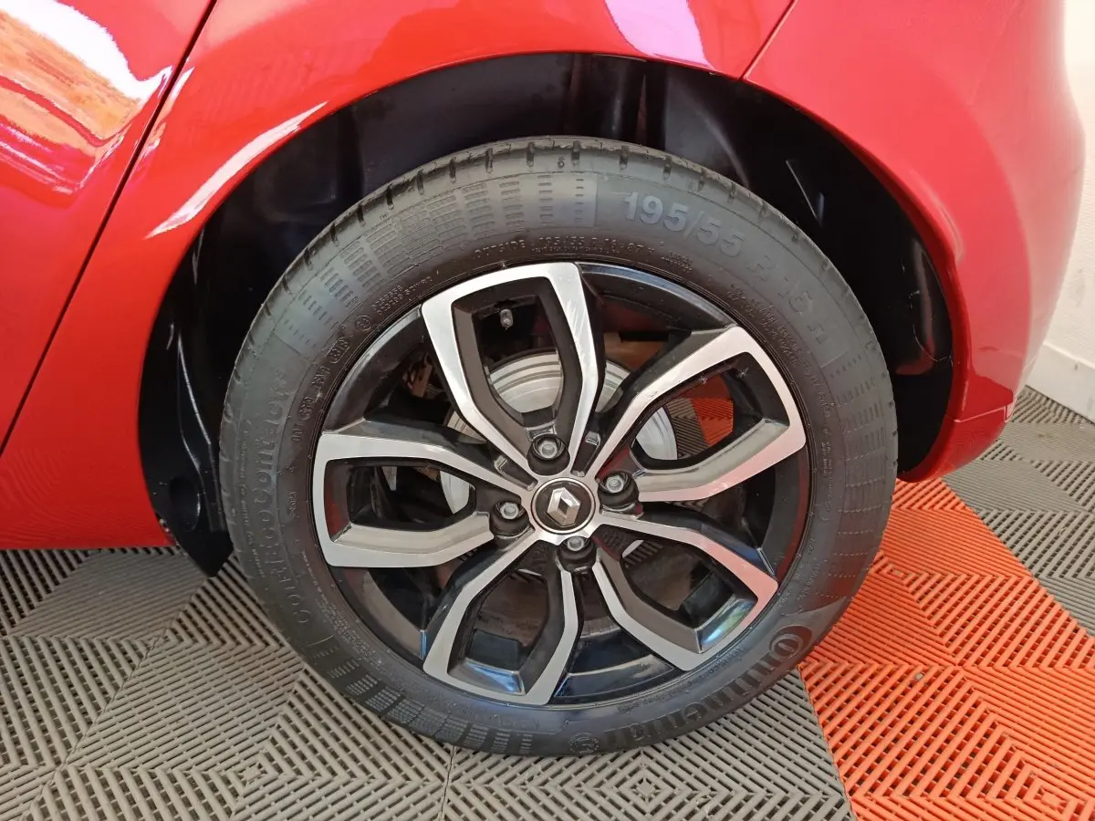 Gros plan sur la roue arrière droite de la Renault Clio rouge, mettant en valeur la jante alliage au design moderne.
