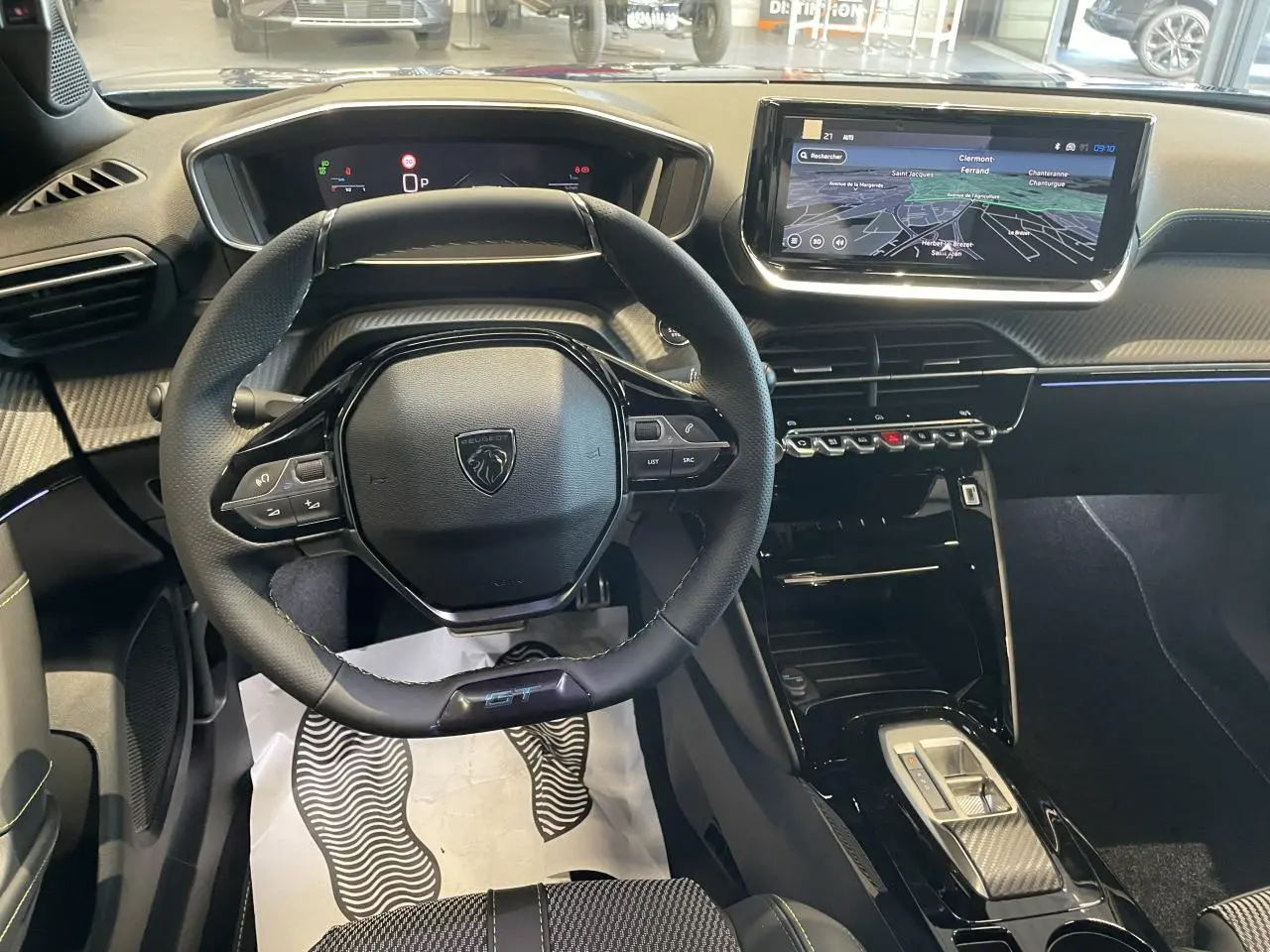 Vue intérieure centrée sur le volant compact Peugeot 2008 GT avec écran tactile 10'' et finitions carbone et surpiqûres vertes