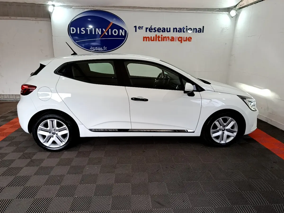 Profil droit d'une Renault Clio Business blanche 2021, avec jantes alliage et poignées de porte noires visibles.