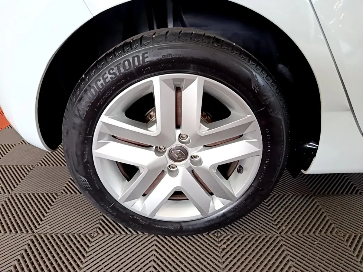 Gros plan sur la roue arrière droite d'une Renault Clio blanche 2021, avec partie de la carrosserie visible.