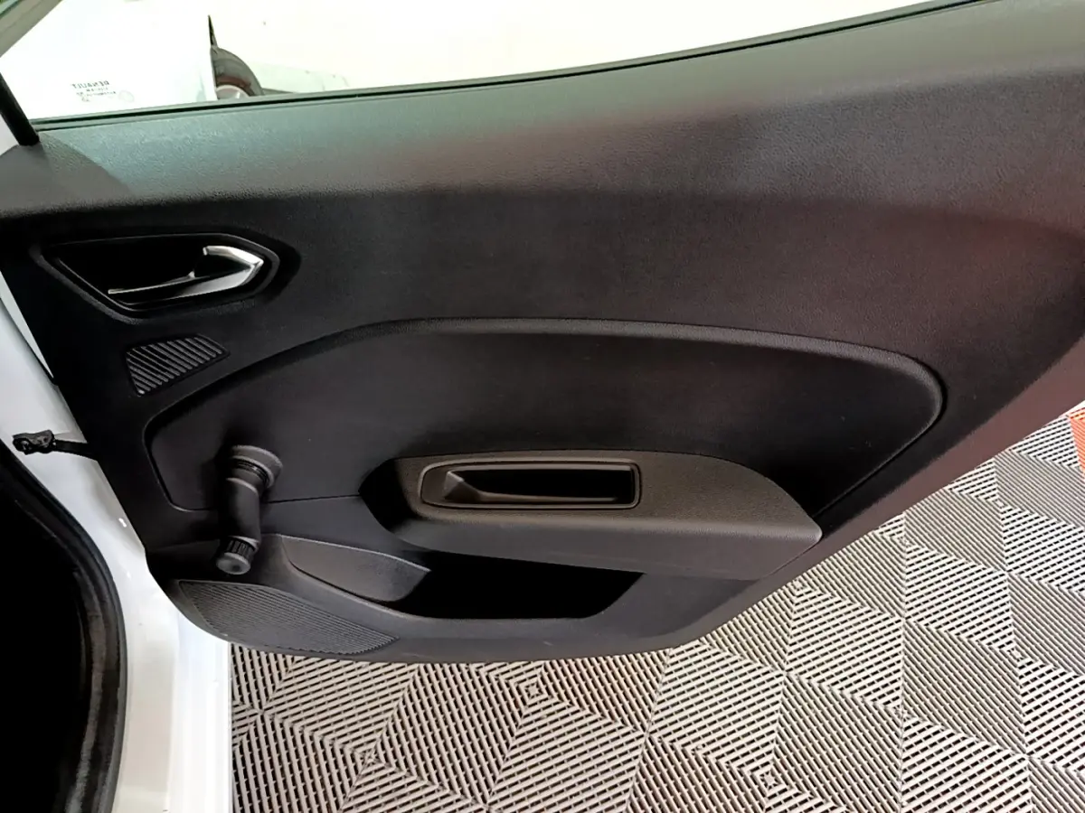 Vue rapprochée de la porte intérieure côté gauche noire de la Renault Clio Business blanche, avec manivelle de vitre visible.