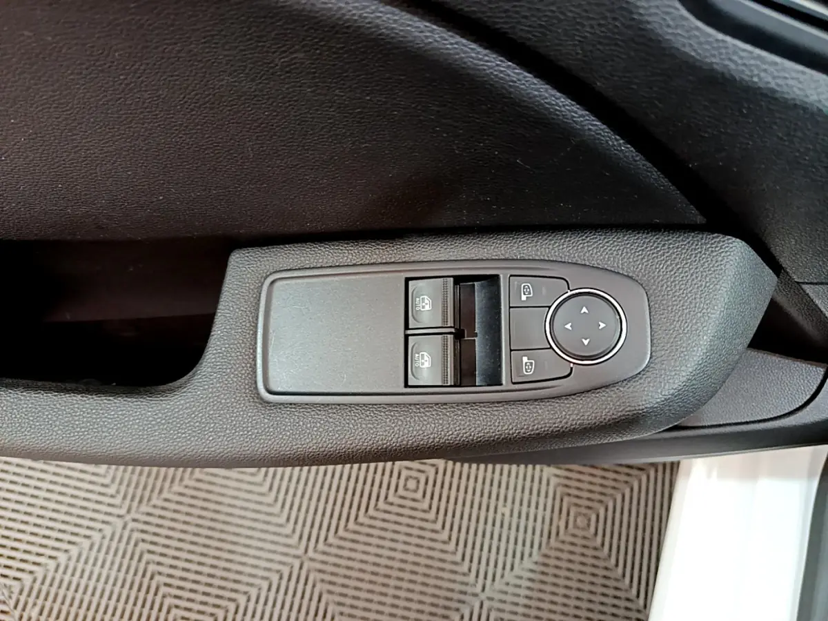 Gros plan sur les commandes de lève-vitres et réglage des rétroviseurs côté conducteur de la Renault Clio Business blanche 2021.