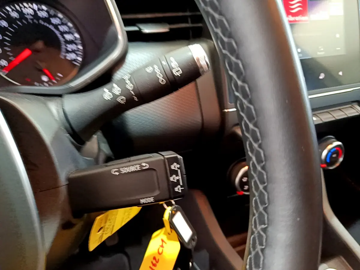 Gros plan sur le volant et commandes de la Renault Clio Business blanche, avec tableau de bord et écran tactile visibles.