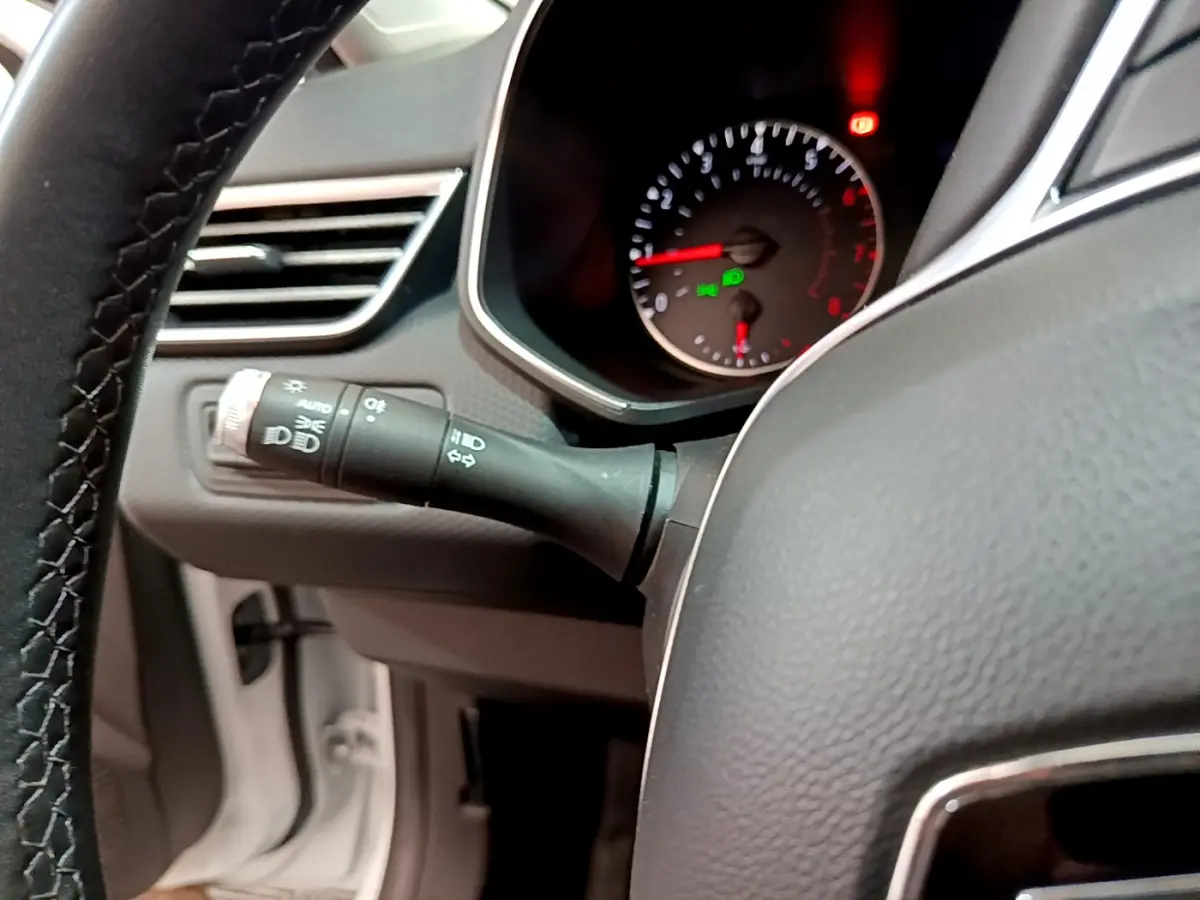 Gros plan sur la manette des phares et le compteur de vitesse du tableau de bord de la Renault Clio Business blanche 2021.