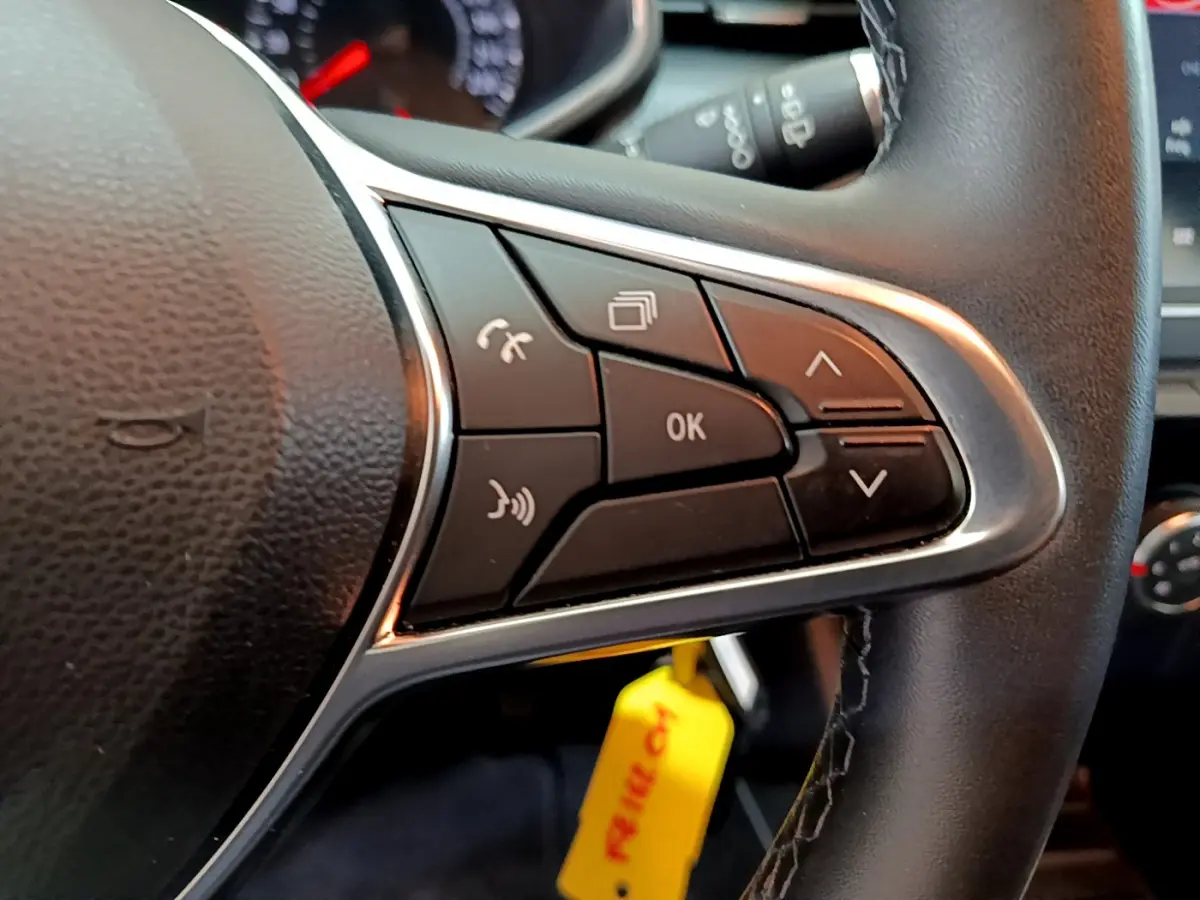 Gros plan sur les commandes multifonctions du volant cuir noir de la Renault Clio Business blanche de 2021.