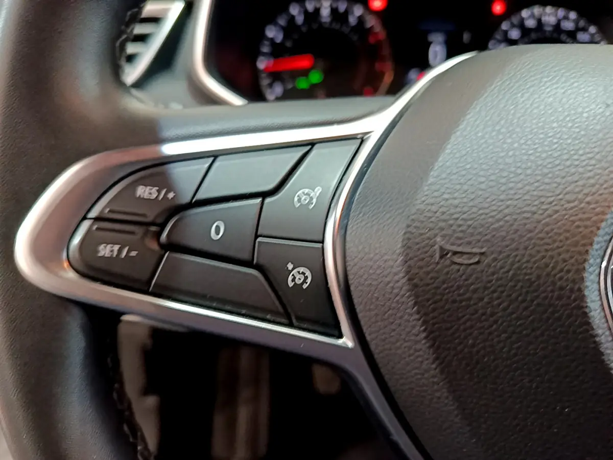 Gros plan sur les commandes du volant côté gauche de la Renault Clio Business blanche, avec tableau de bord flou en arrière-plan.