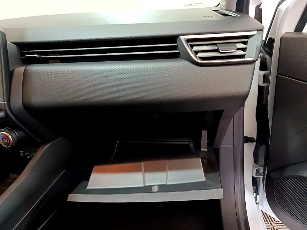 Intérieur côté passager d'une Renault Clio Business blanche 2021, boîte à gants ouverte et tableau de bord gris.