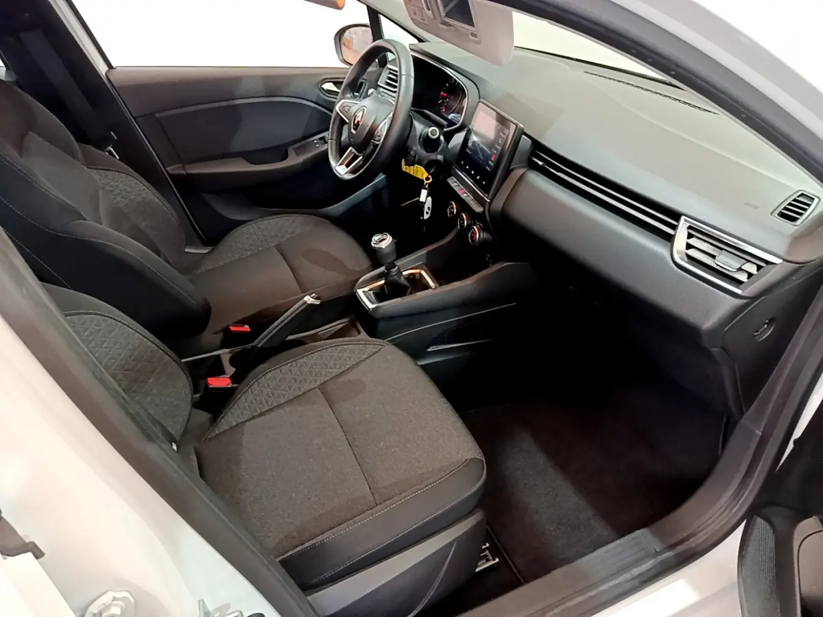 Intérieur avant droit de la Renault Clio Business blanche, sièges noirs, volant cuir et écran tactile central visible.