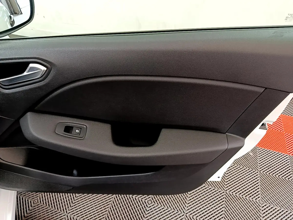 Gros plan sur la porte côté gauche d'une Renault Clio Business blanche, avec commande de vitre électrique noire.