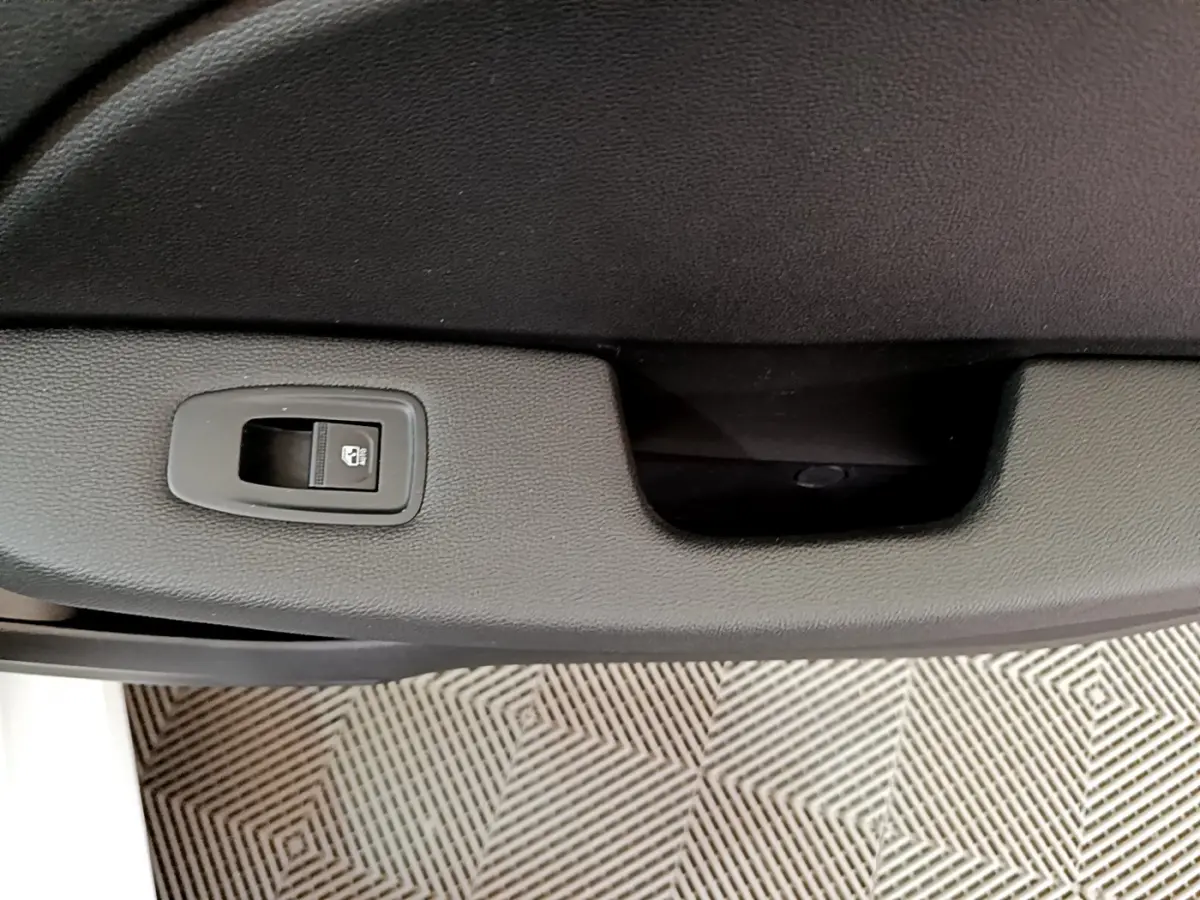 Gros plan sur la commande de verrouillage de porte noire dans l'habitacle d'une Renault Clio Business blanche, côté conducteur.