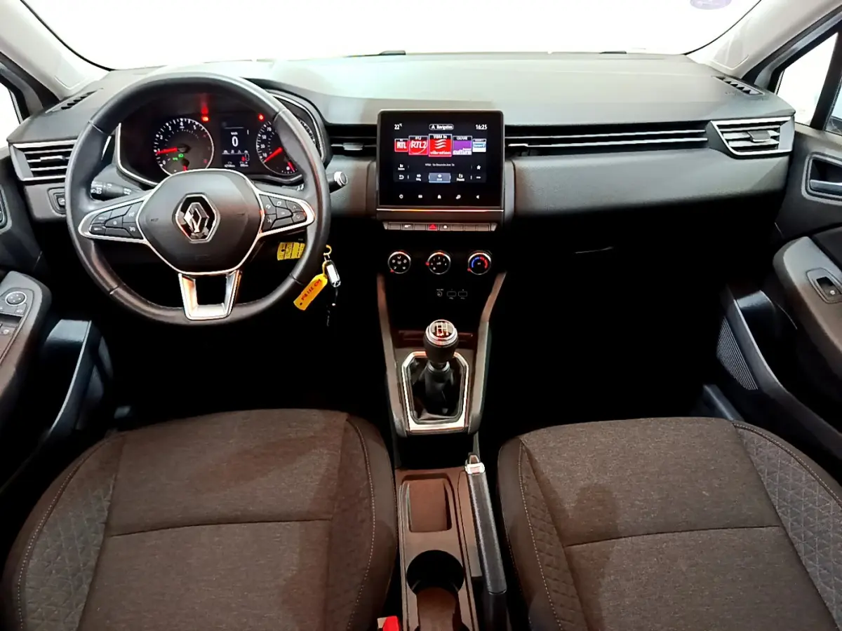 Vue intérieure avant de la Renault Clio Business blanche 2021, volant cuir, écran tactile et boîte manuelle visible.