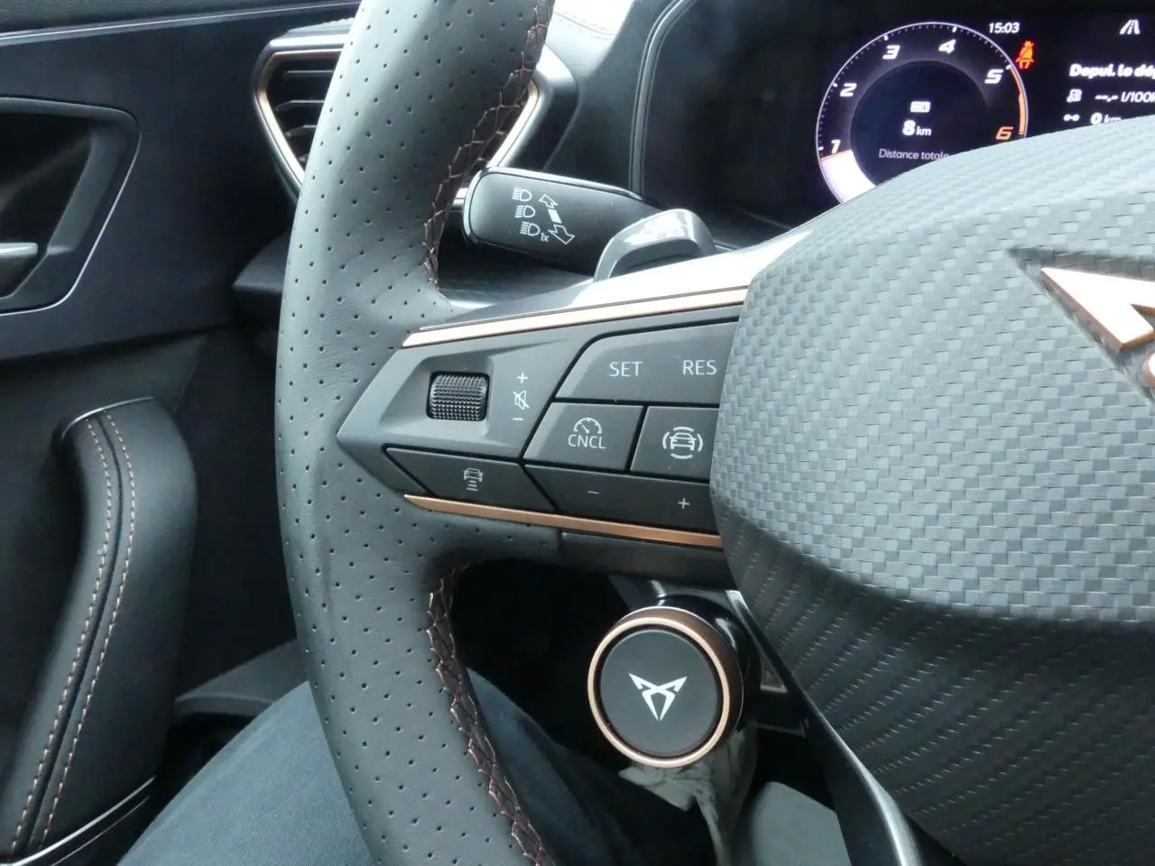 Gros plan sur le volant perforé noir avec surpiqûres cuivrées et commandes multifonctions du CUPRA Formentor gris Graphène 2025.