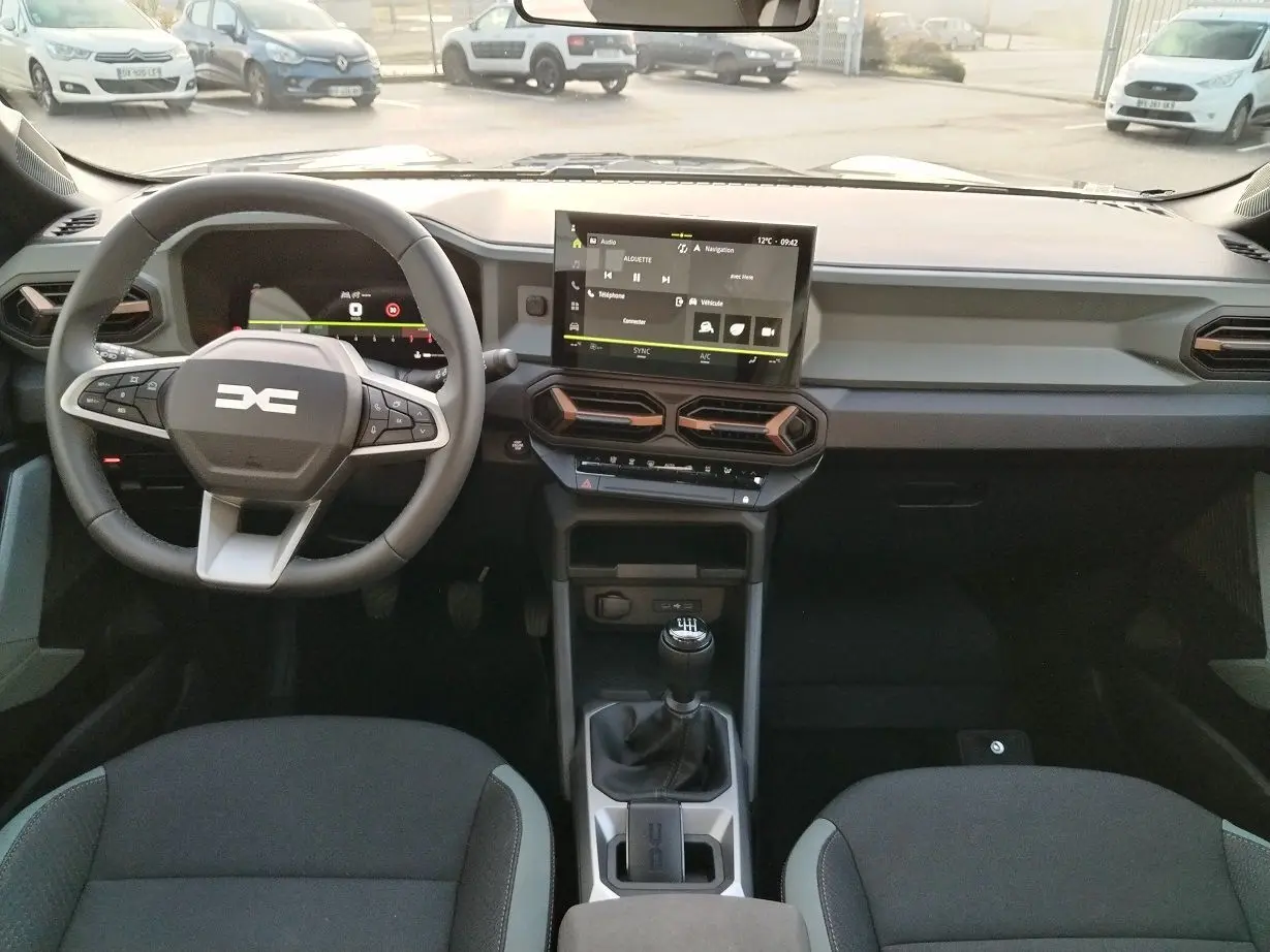 Intérieur du Dacia Bigster 2025 en vue frontale, tableau de bord moderne avec écran tactile et levier de vitesses manuel.