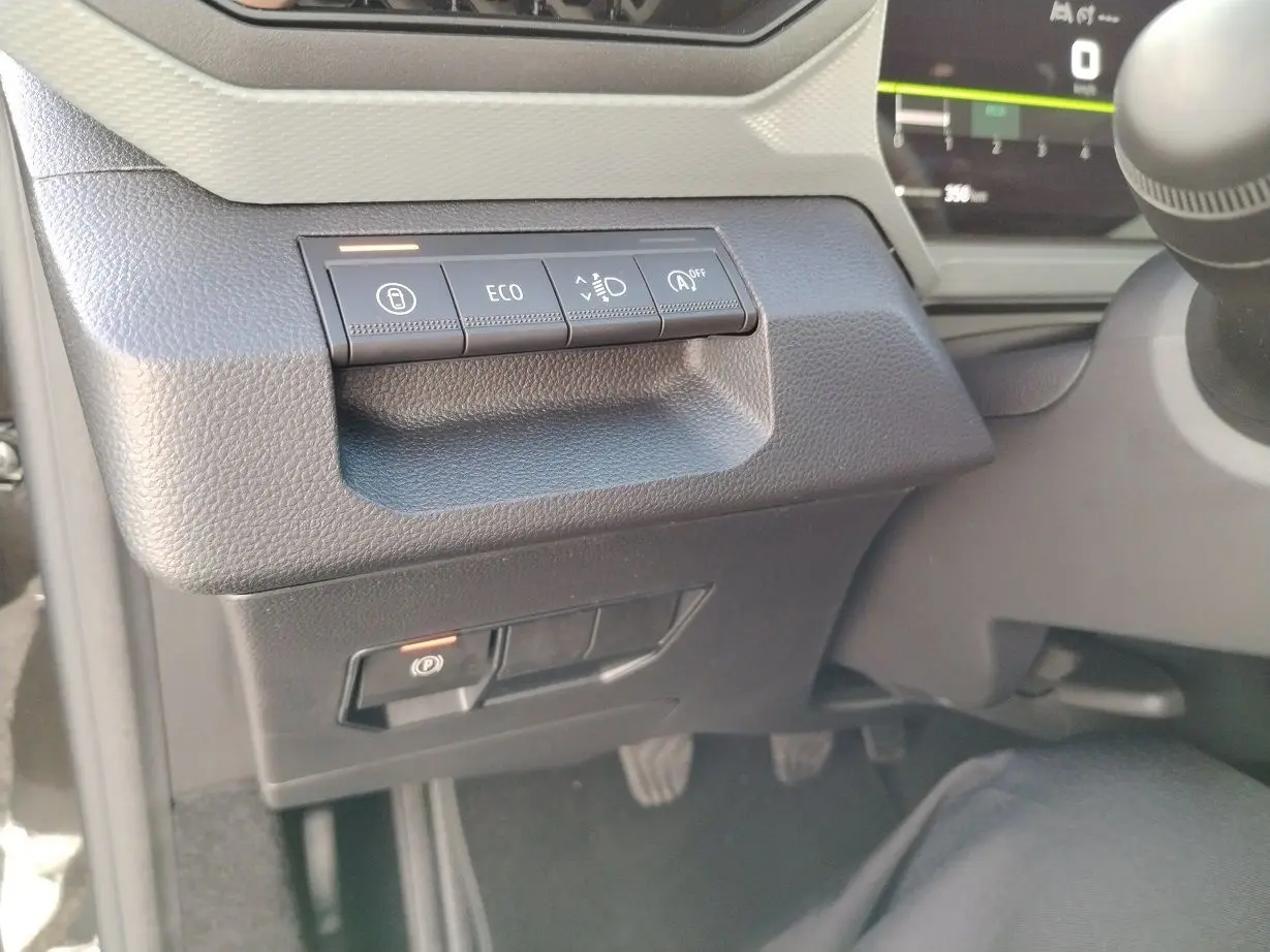Gros plan sur les commandes à gauche du volant dans l'habitacle noir du Dacia Bigster 2025, avec bouton ECO et frein à main électronique.