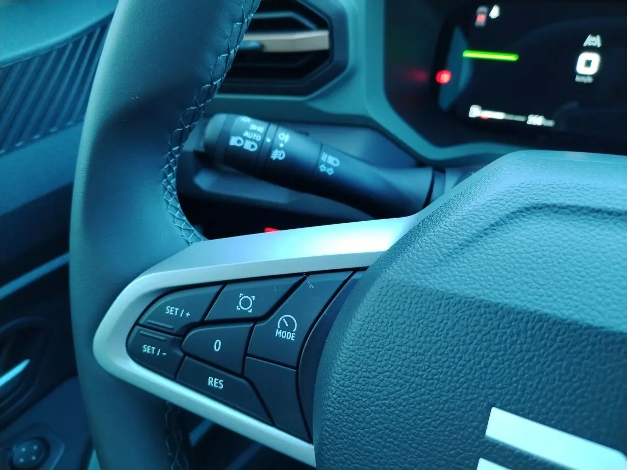 Gros plan sur le volant noir du Dacia Bigster 2025, avec commandes multifonctions et tableau de bord numérique en arrière-plan.