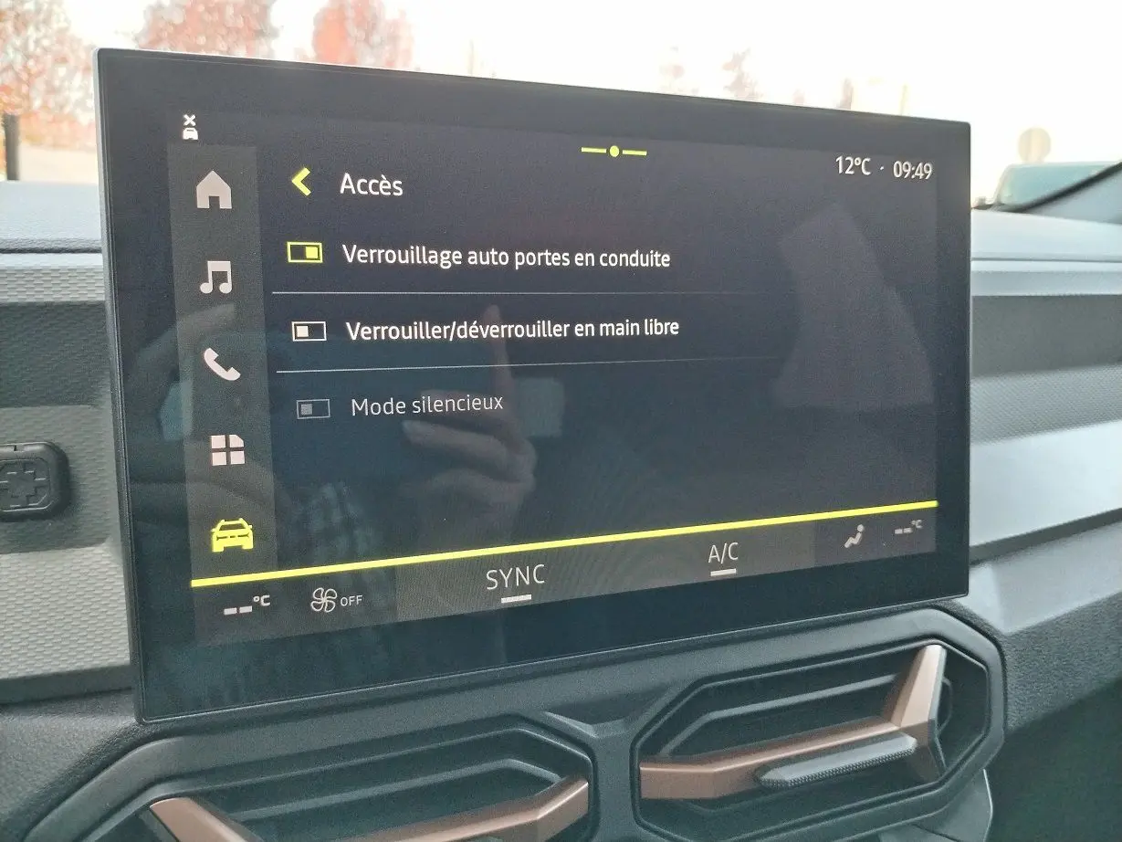 Écran tactile central affichant les réglages d'accès du DACIA BIGSTER 2025, intérieur moderne avec aérateurs hexagonaux.