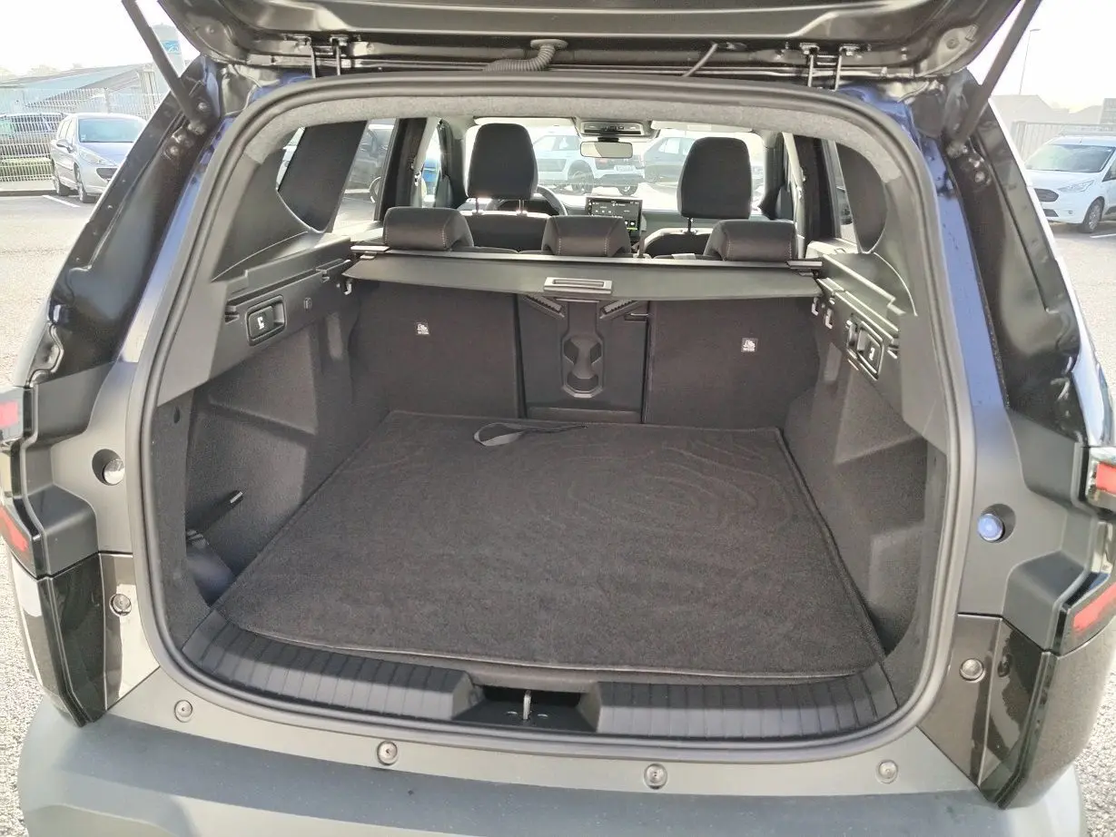 Vue arrière du coffre ouvert d'un Dacia Bigster noir 2025, montrant l'espace de chargement et la banquette arrière.