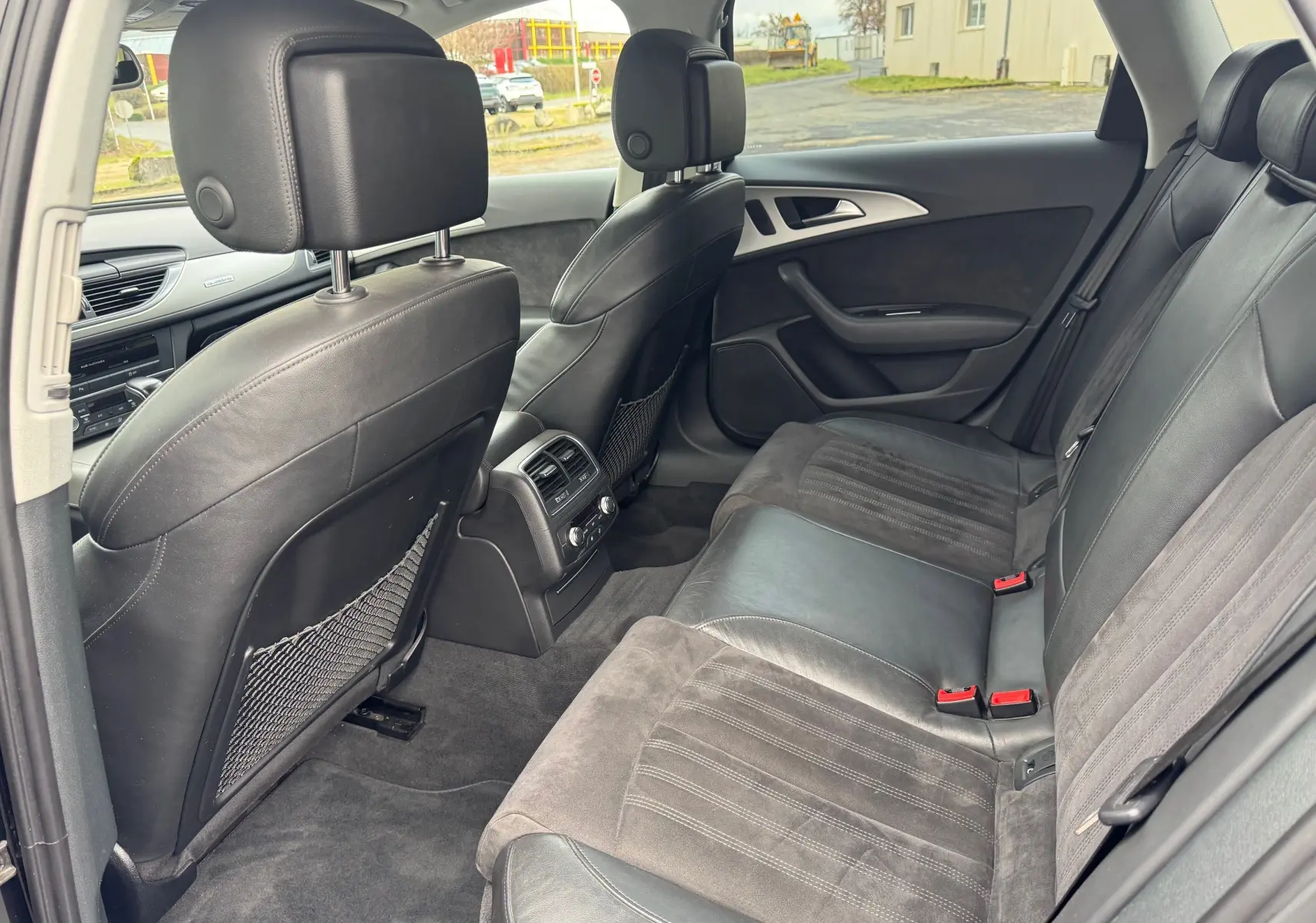 Vue intérieure arrière côté droit de l’Audi A6 Avant 2015 noire, sièges en cuir et alcantara avec console de climatisation arrière.