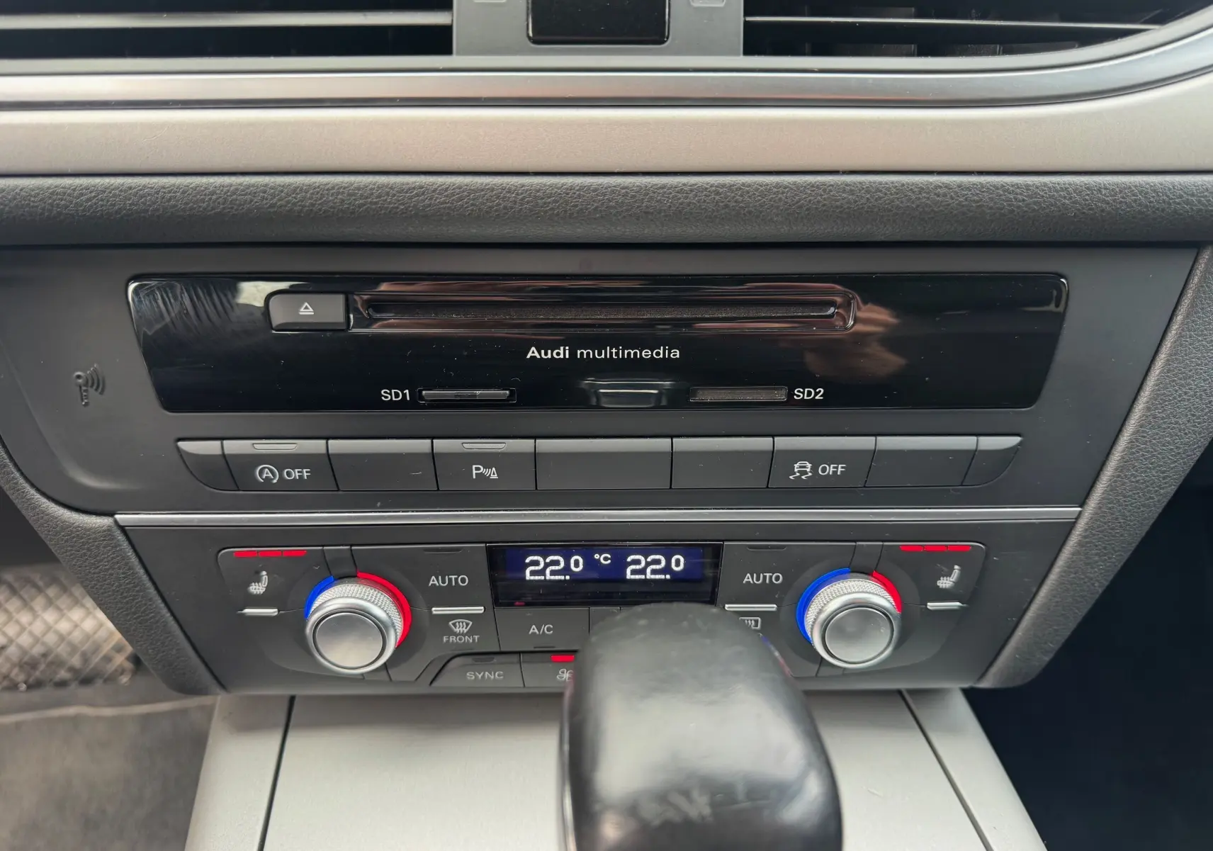 Gros plan sur la console centrale noire de l'Audi A6 Avant 2015, montrant la climatisation digitale et le levier de vitesse automatique.